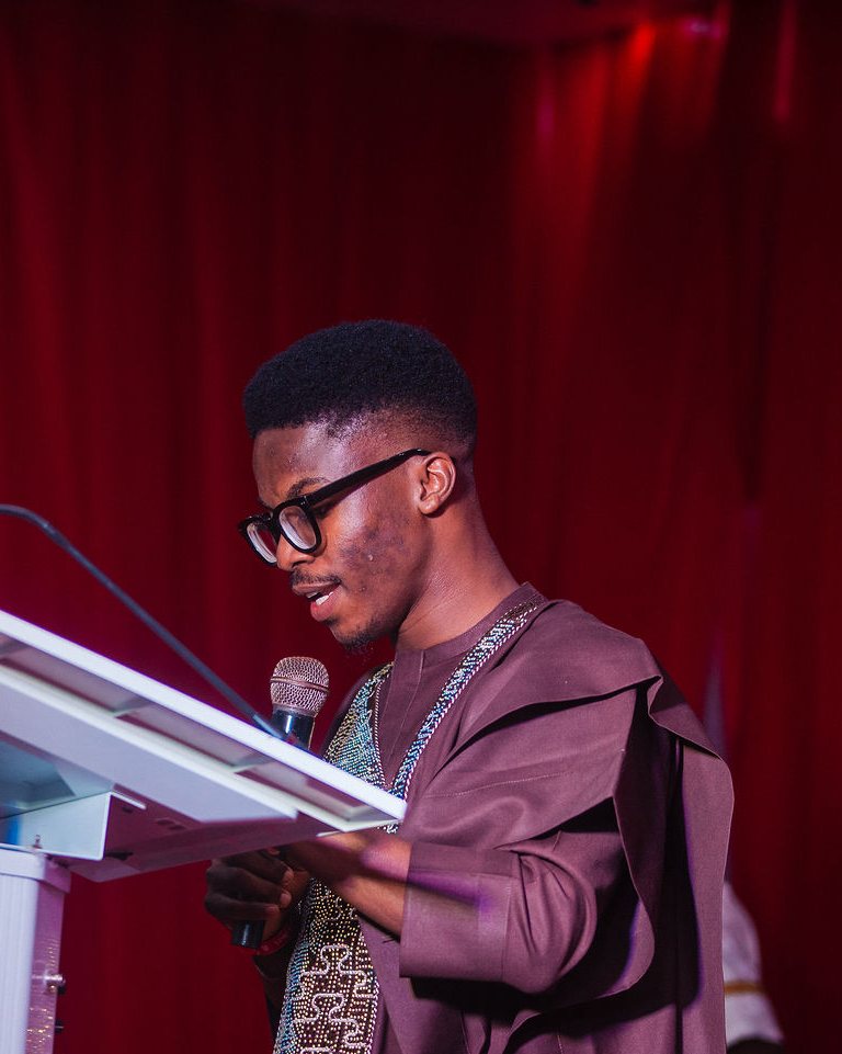 Nothing crossing the face; the mic and hands stay below the chin.
